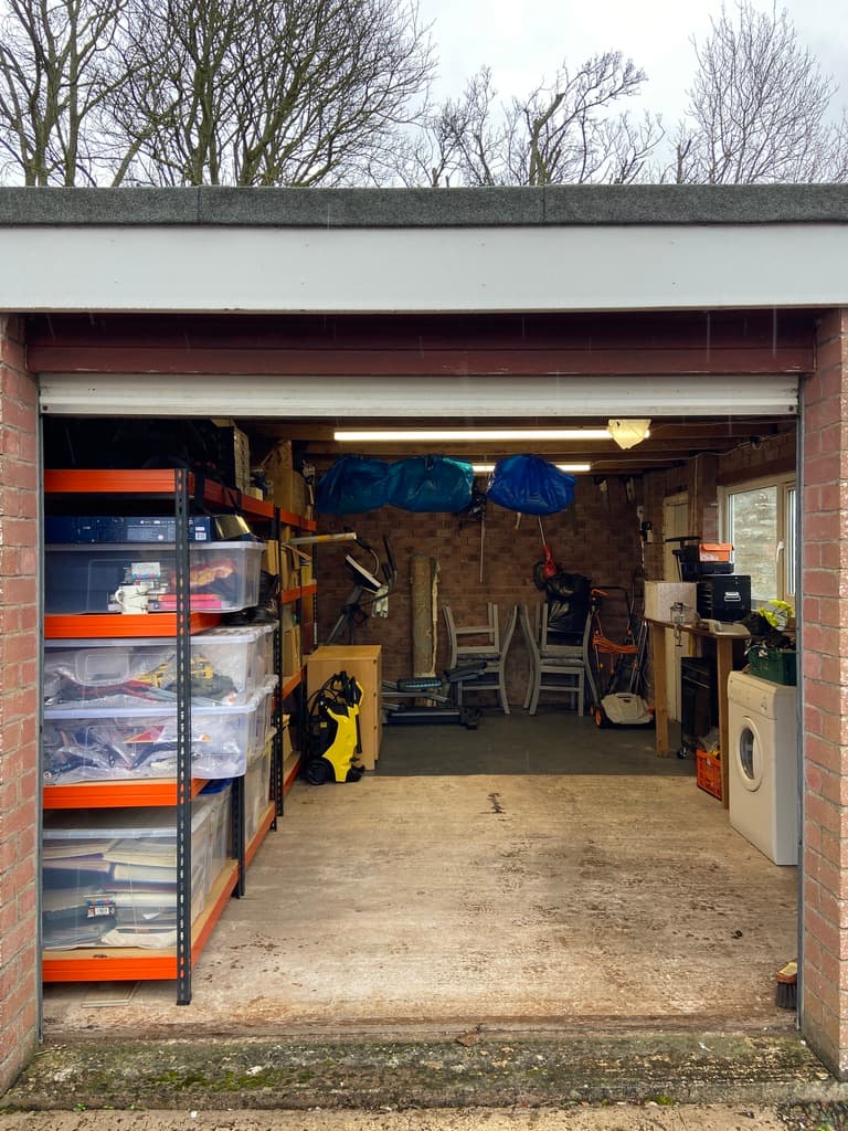 Cluttered garage packed with shelving, boxes and equipment before a professional clearing