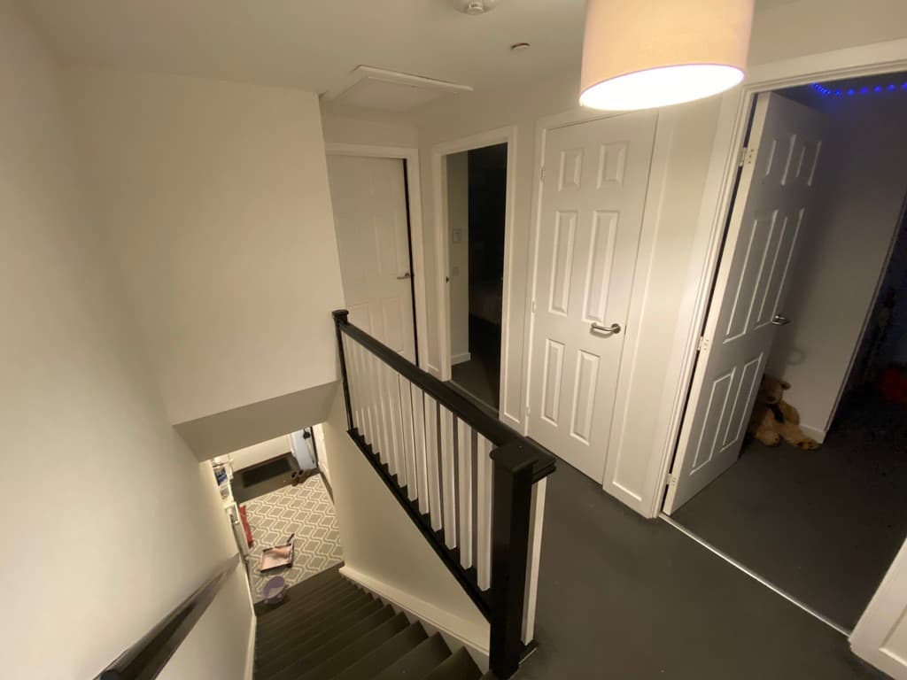 Bright stairwell with crisp white walls and dark handrail